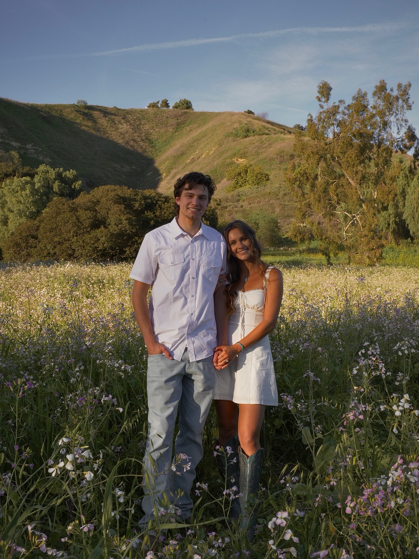 Will and Emma standing together in a wildflower meadow